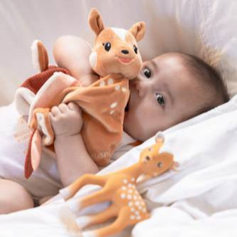 Baby holding a plush deer toy on a soft white background