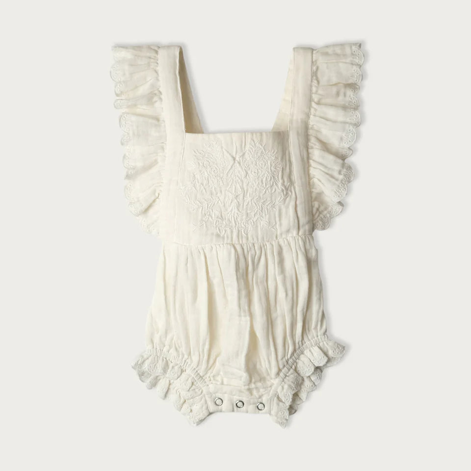 White baby romper with ruffled details on a white background