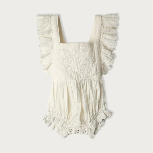 White baby romper with ruffled details on a white background