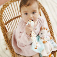 Load image into Gallery viewer, Baby sitting in a wicker chair holding a plush toy
