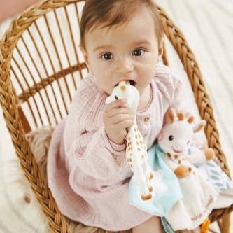 Baby sitting in a wicker chair holding a plush toy